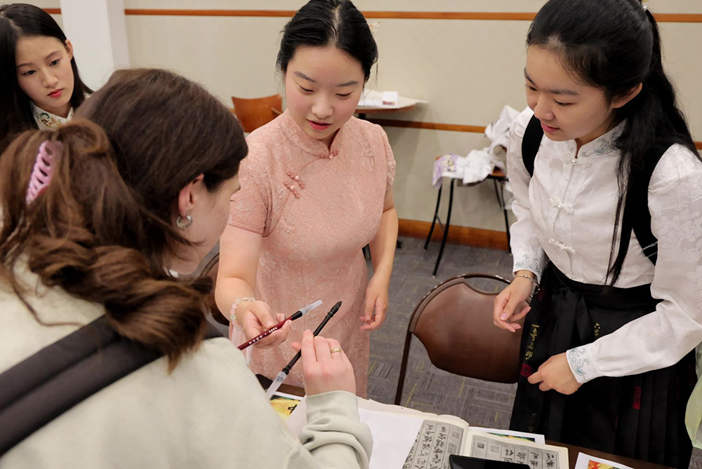 Two Chinese students showing an American student how to hold a caligraphy brush at UNC Pembroke.