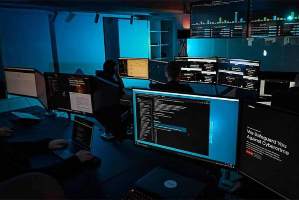 Dark computer lab full of students on computers with screens full of code.