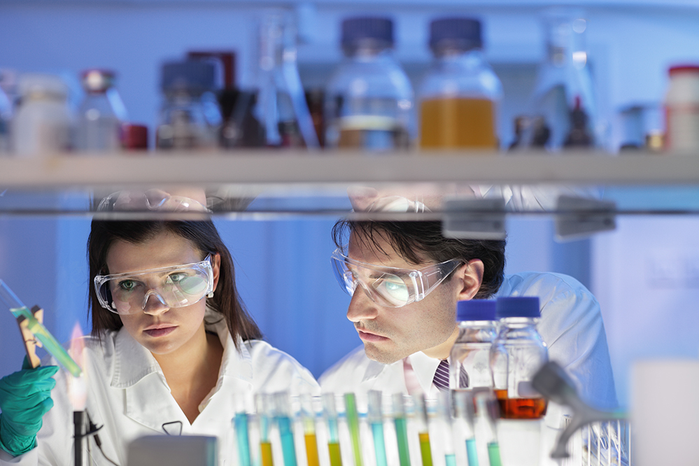 faculty wearing googles and working on an experiment in a science lab