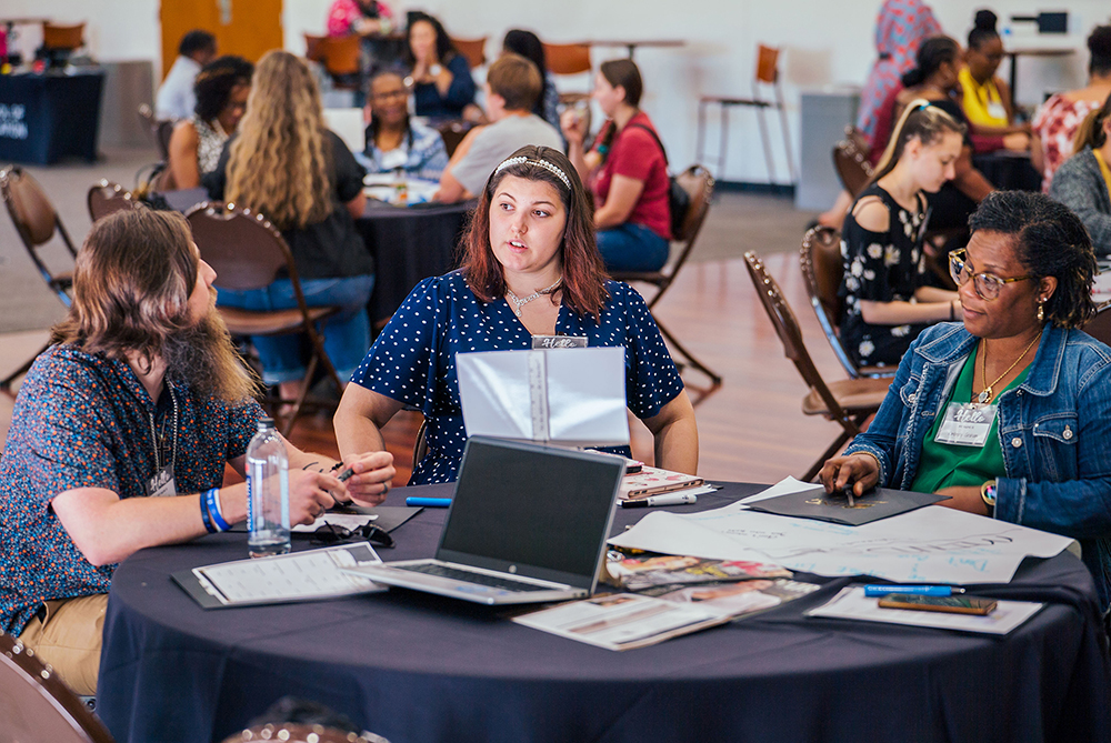 community members sitting around a table at a symposium on the campus of UNC Pembroke