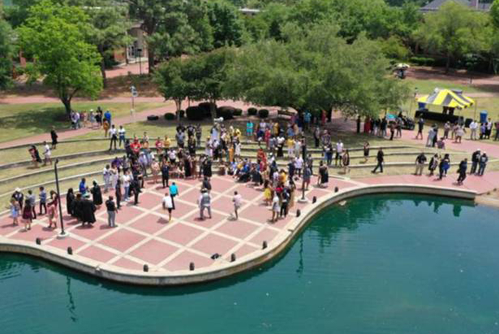 Drone image of people gathered in the amphatheatre, next to the water feature, on the quad of UNC Pembroke.