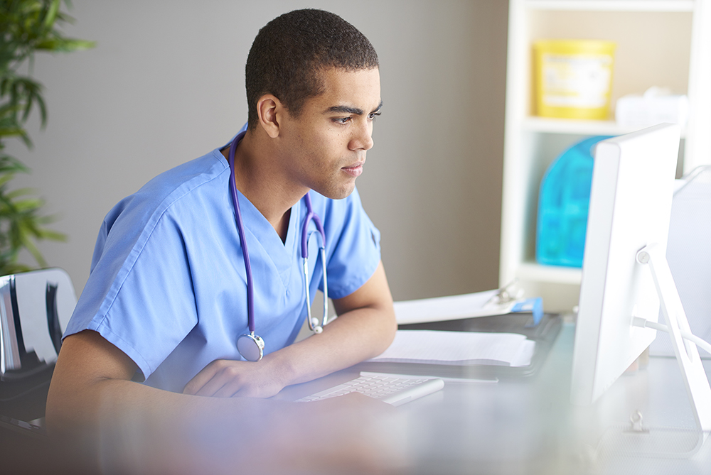 male nursing student watching computer monitor