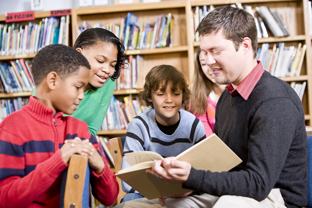 teacher reading with three children in a library setting