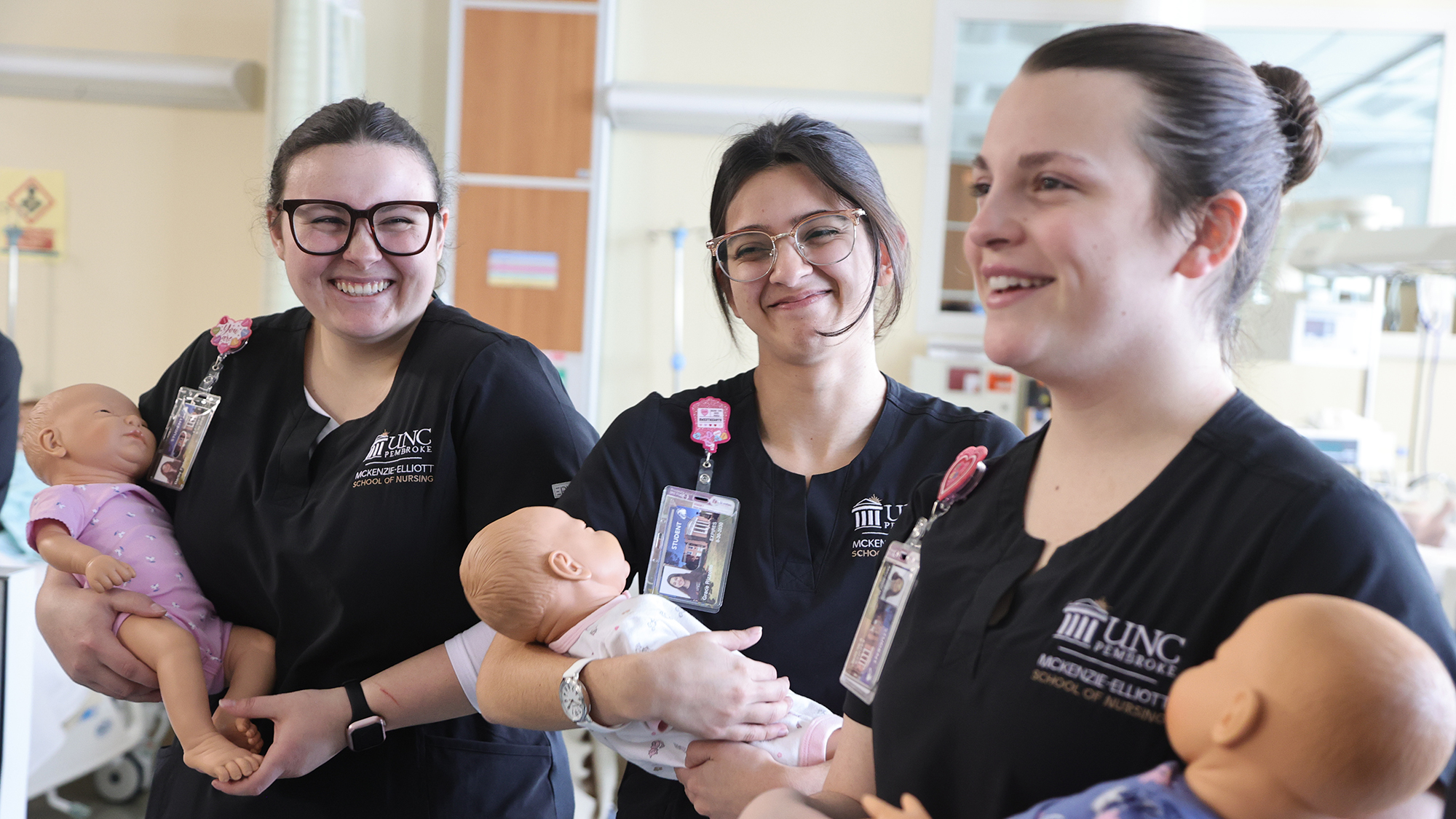 UNCP Nursing students in a clinical setting holding neonates