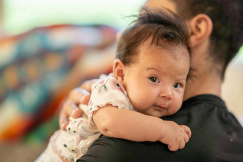 baby on man's shoulder looking at the camera