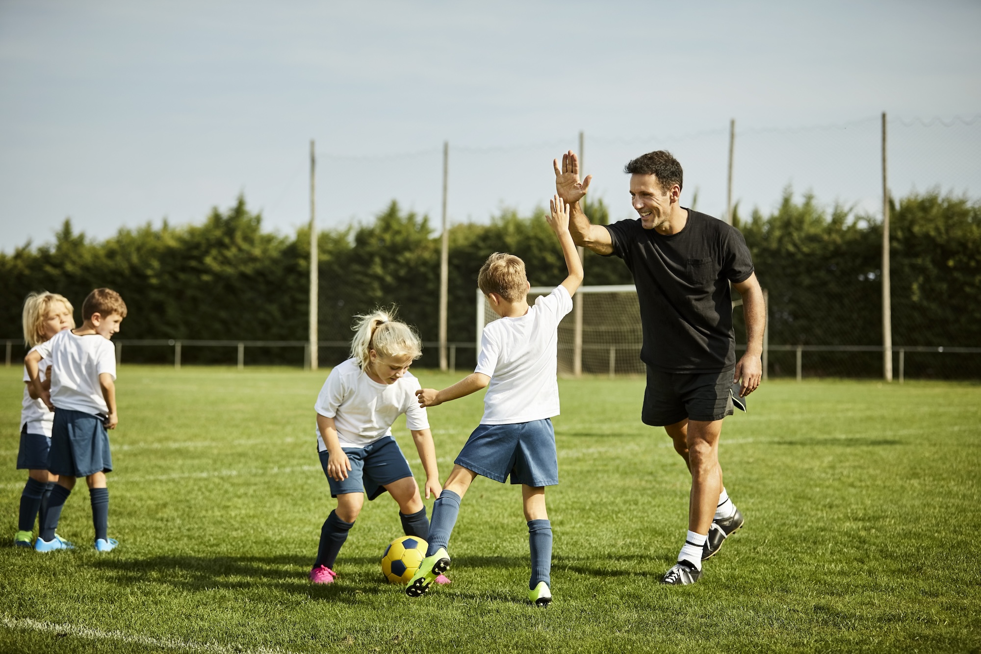 Coach high fiving a kid soccer player