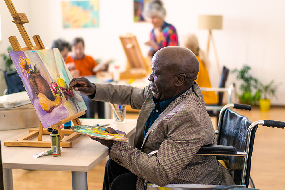 man in wheelchair works on a painting for occupational therapy