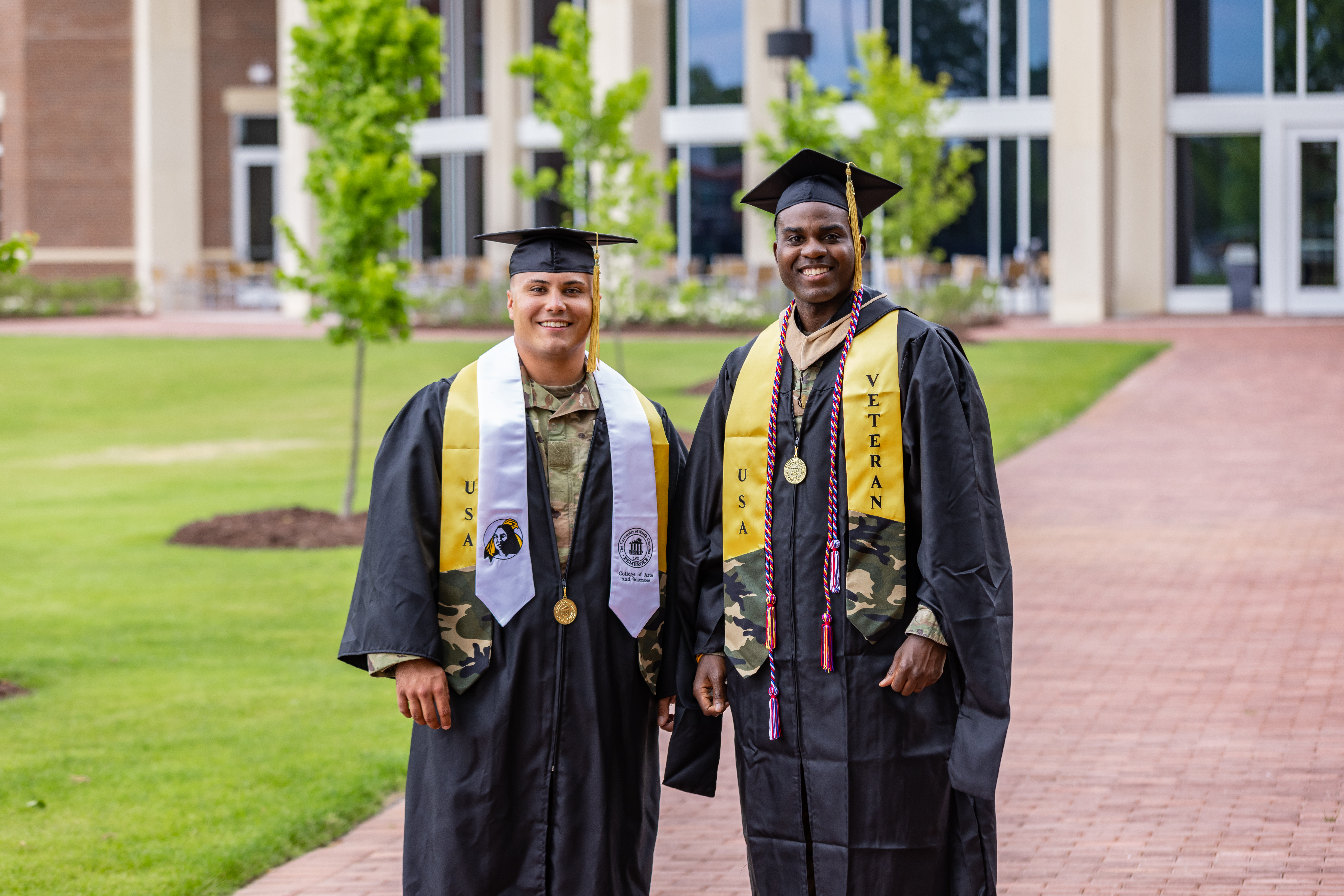 ROTC graduates in cap and gown standing behind Thomas Hall