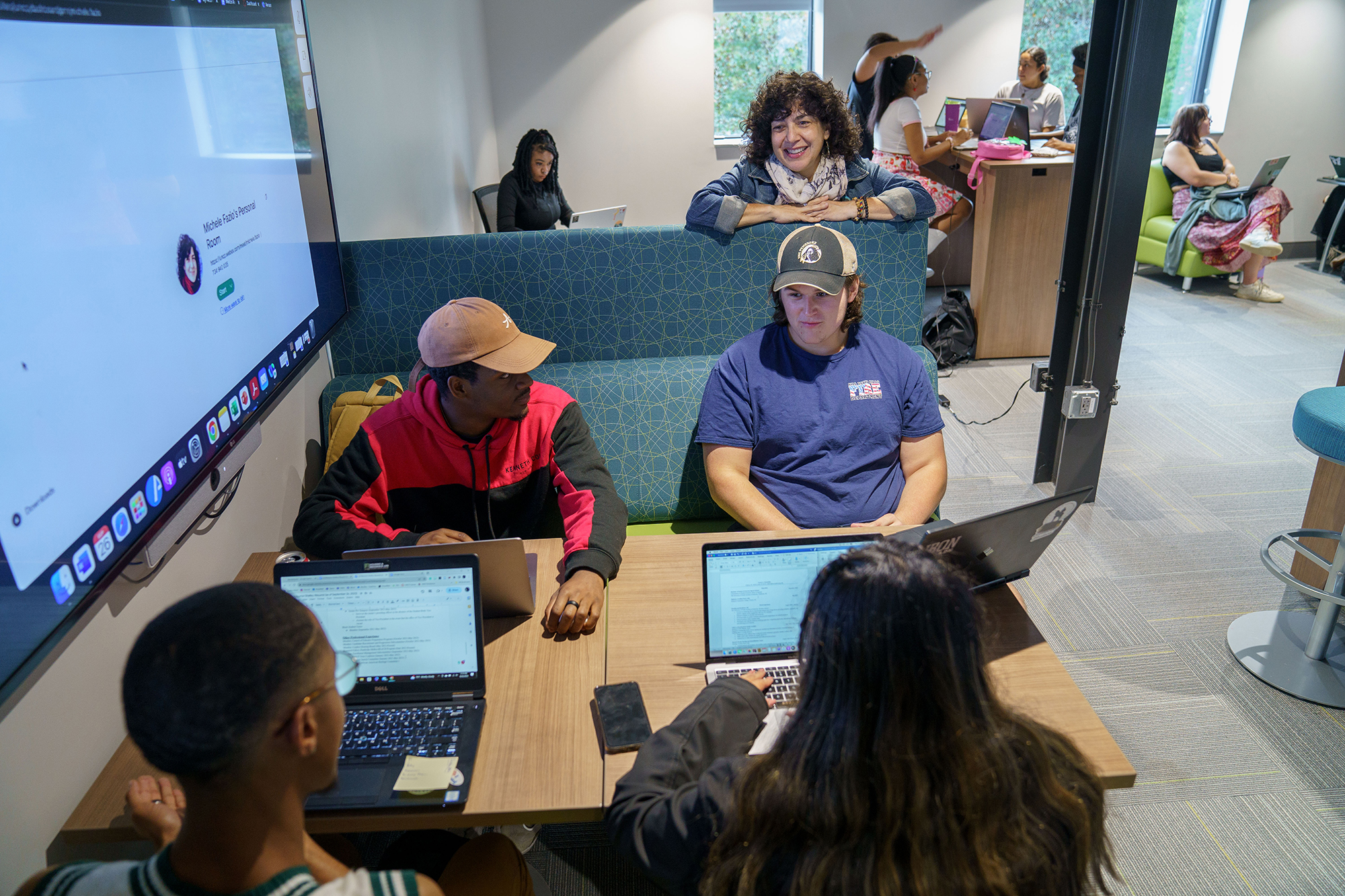 REACH faculty member stands behind a group of students discussing research at UNC Pembroke
