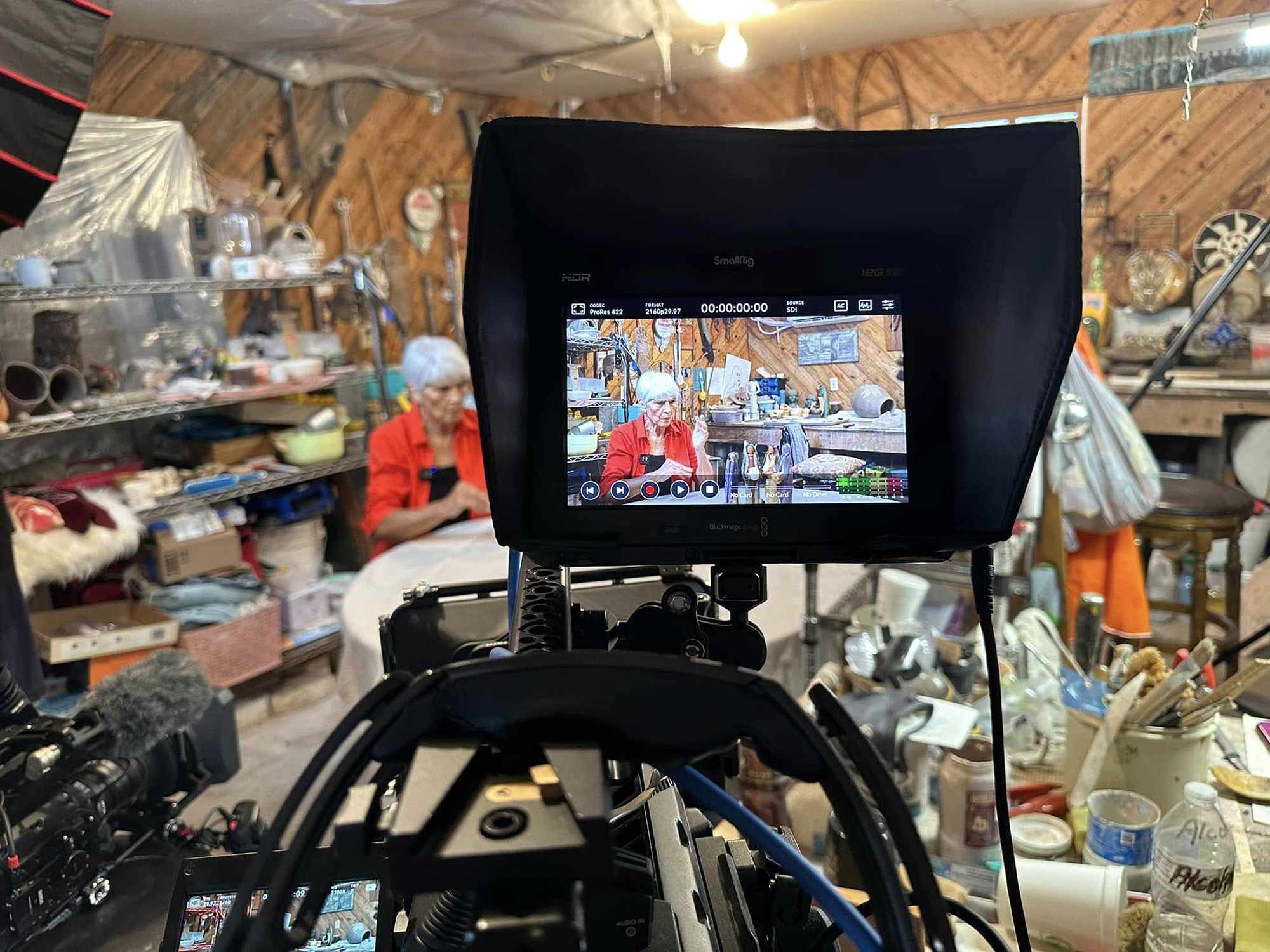 A video camera captures an elder while she demonstrates craft making