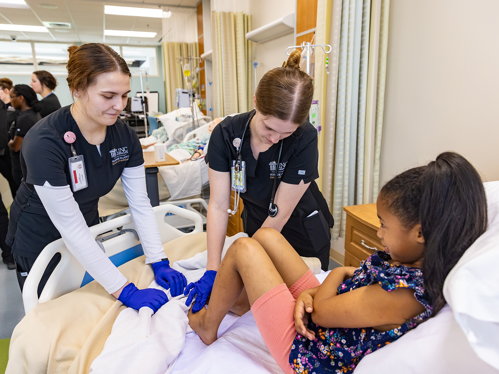 student nurses in scrubs helping patient