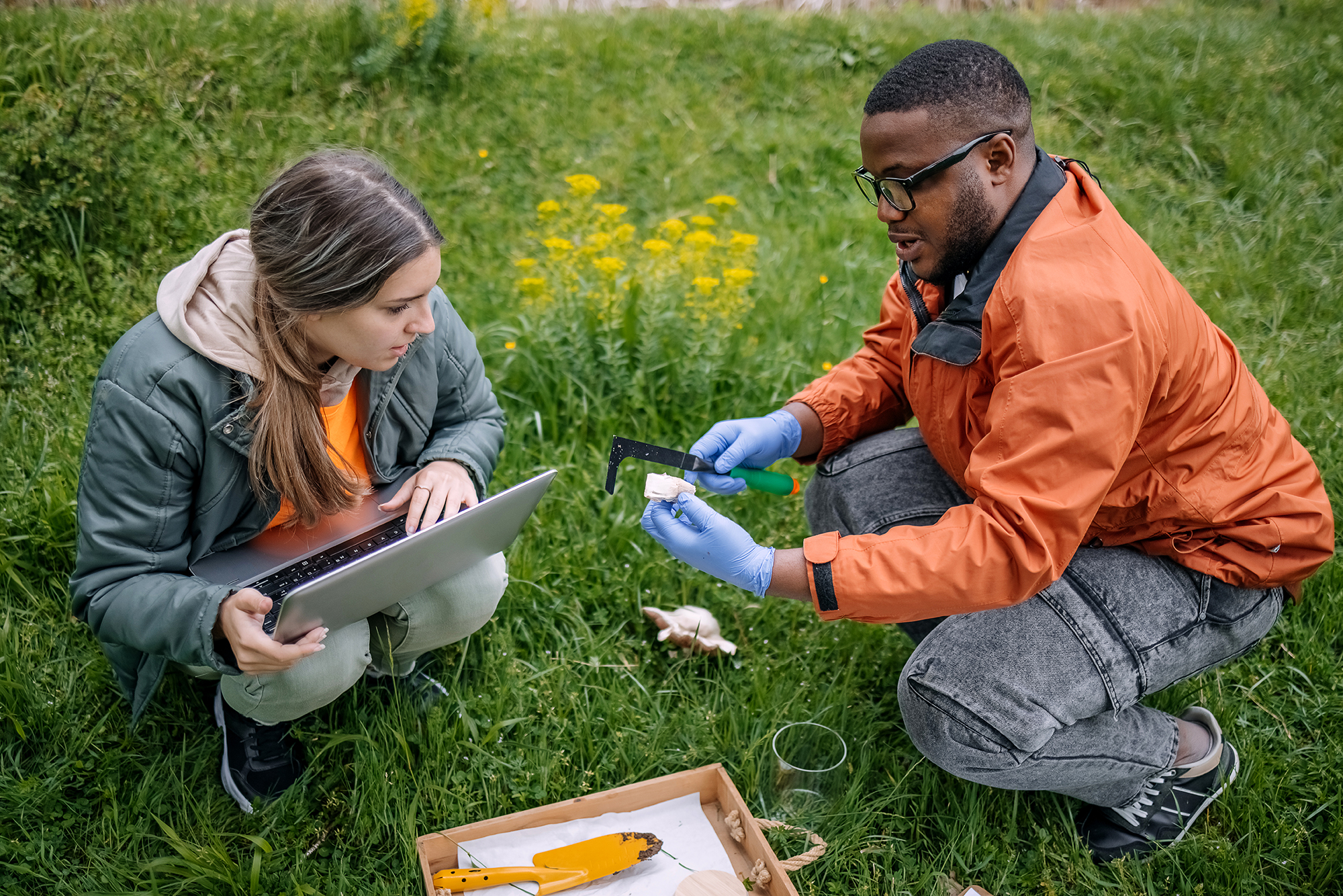 male and female student conducting research in a field