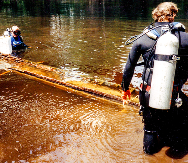 A photo taken in 1984 shows divers removing a 1,100-year-old canoe from the Lumber River