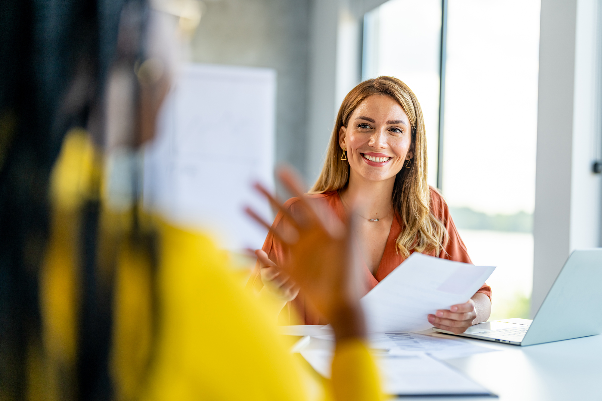 woman talking with another woman over paperwork