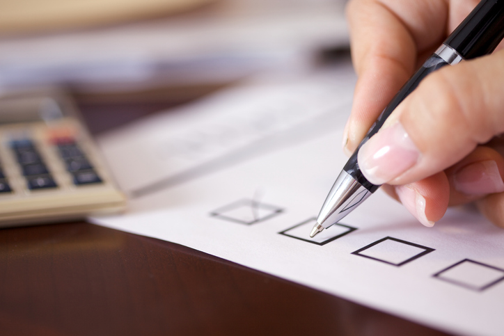 hand holding pen with a checkbox list under it