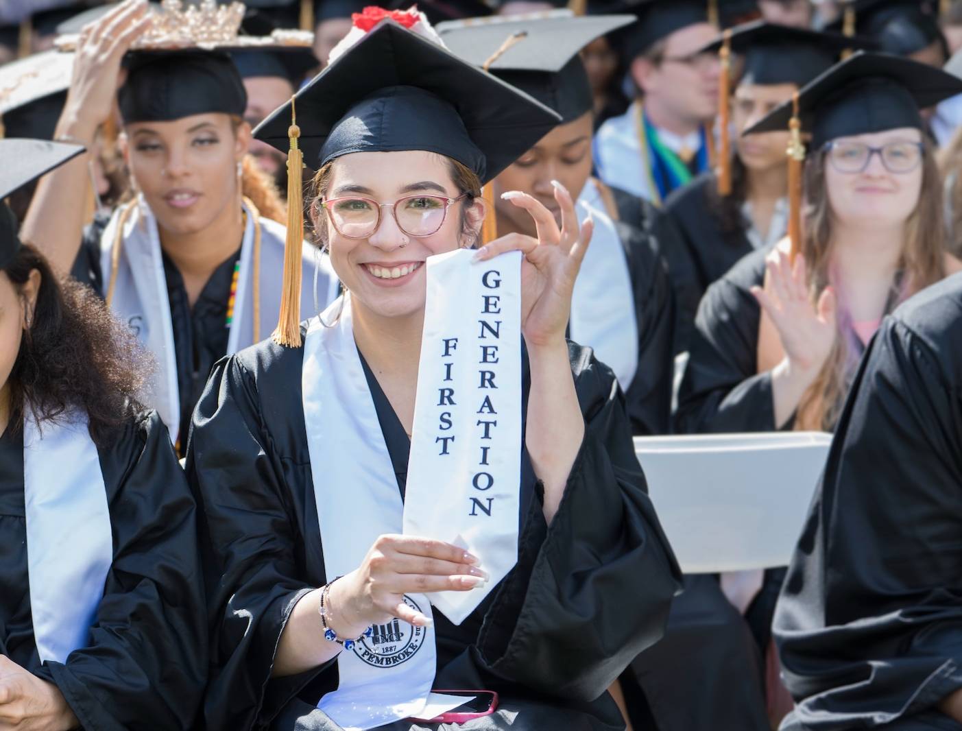 Girl in cap and gown holding up her stole