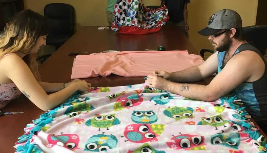 Psi Chi students volunteering to make blankets for the Child Advocacy Center in Fayetteville. We donated 10 blankets and had a lot of fun making them! :-) One of the pictures was taken at the Child Advocacy Center once Babs dropped the blankets off.