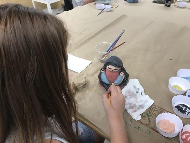 Art education students facilitating an artmaking based on Pueblo storyteller dolls experience with middle school student working. 