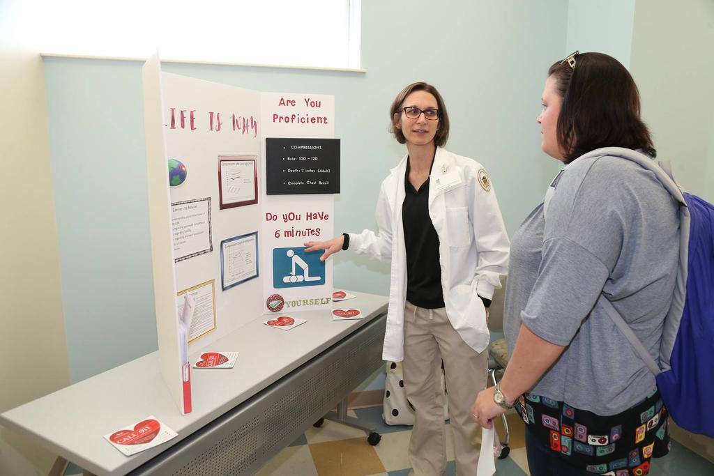 A nursing student teaches another individual about her project.