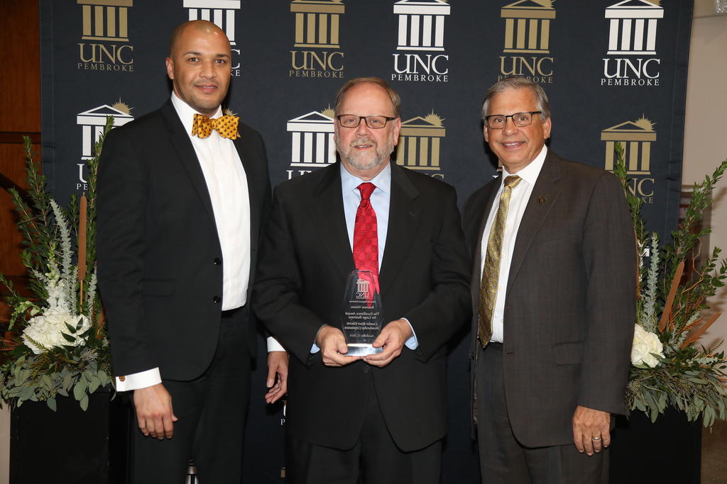 Walter White accepts the Excellence Award for Large Business on behalf of Lumbee River Electric Membership Corporation. He is pictured with Patrick Strickland and Chancellor Cummings