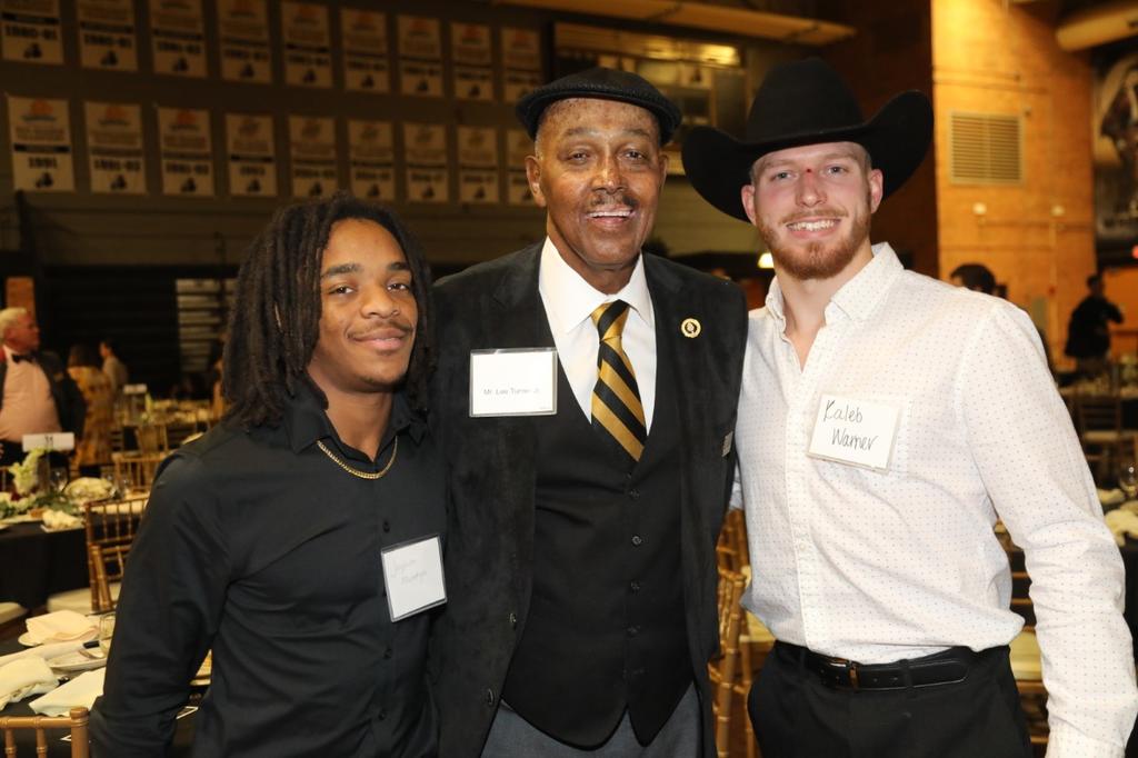 Jayquon McEntryre and Kaleb Warner pose with longtime UNCP supporter Lee Turner
