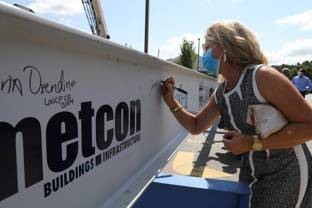 Jodi Willis, daughter of Mary and the late Wyatt Upchurch, signs the final beam during at the topping out ceremony on July 23, 20202
