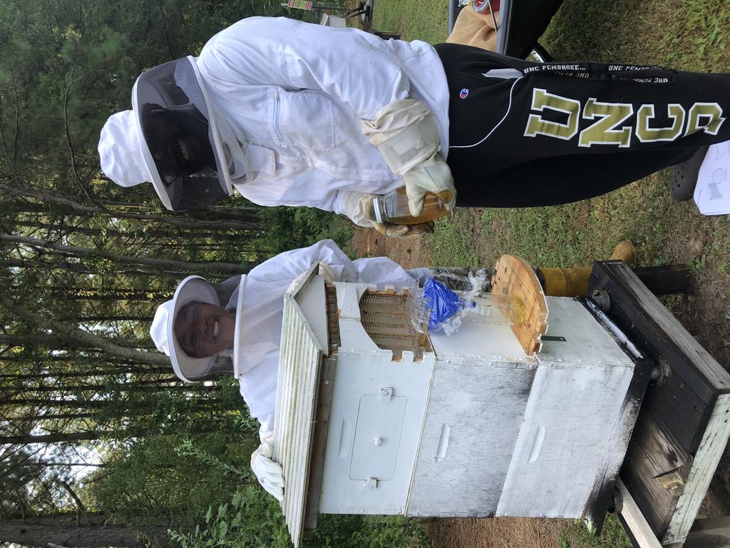 two students stand with a flow hive