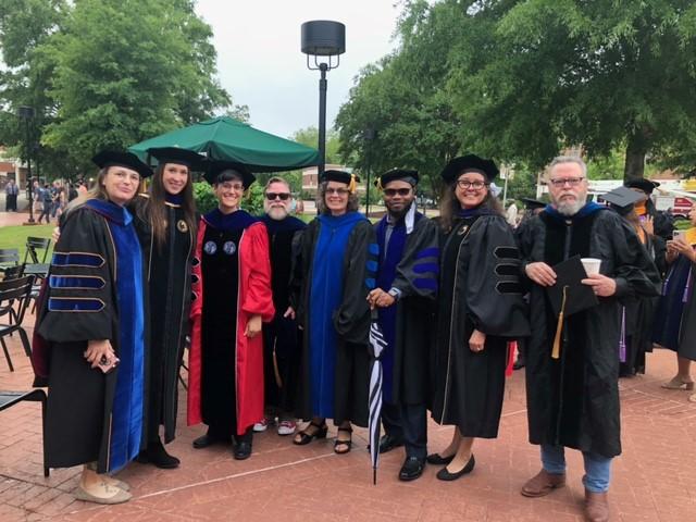 SOCJ Faculty at graduation in May 2022 - (Standing left to right) Drs. Renee Lamphere, Corey Pomykacz, Victoria Kurdyla, John Lillis, Brooke Kelly, Yawo Bessa, Lauren Norman, and Michael Spivey.