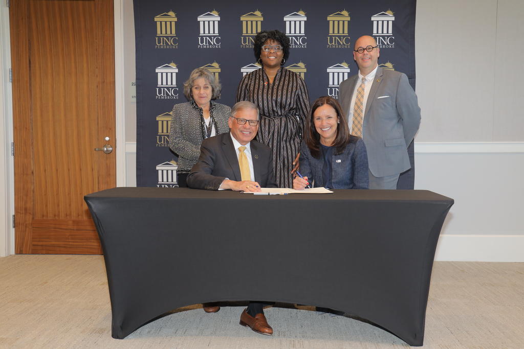 Chancellor Robin Gary Cummings (seated) and Peace Corps Director Carol Spahn sign the Peace Corps Prep Program MOA extension with interim Provost Dr. Cherry Beasley (standing), Lauren Stephens and Dr. Jeff Howard