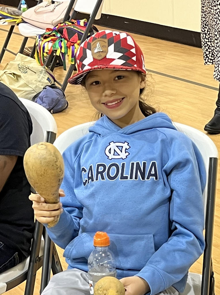 Child with red hat and UNC hoodie at Canoe Song Workshop.