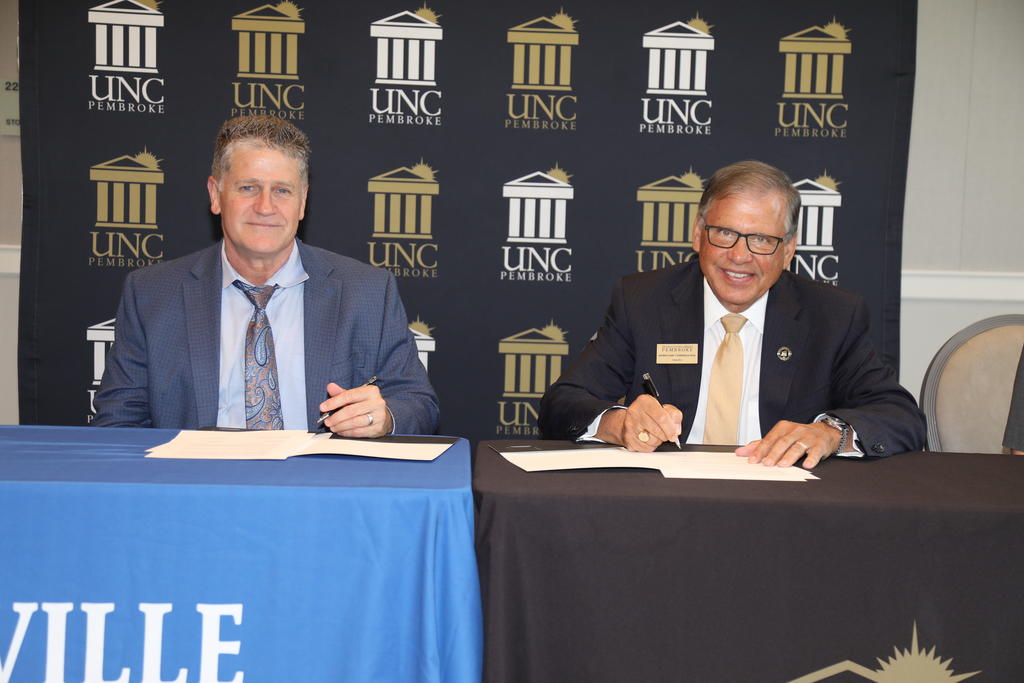 Blair Fisher (left) Head of School at Fayetteville Academy and Chancellor Robin Gary Cummings sign an agreement establishing the UNCP and Fayetteville Academy Joint Enrollment Partnership