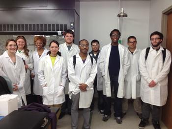 Cohort 8 RISE Fellows standing in lab coats, taking a group picture.