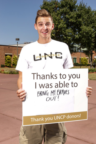 Male student holding a sign thanking donors for their contribution. 