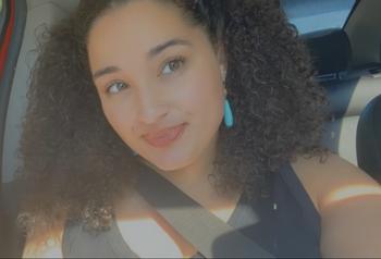 girl smiling with curly hair and turquoise earrings