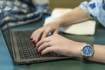 A women's hands typing on a laptop