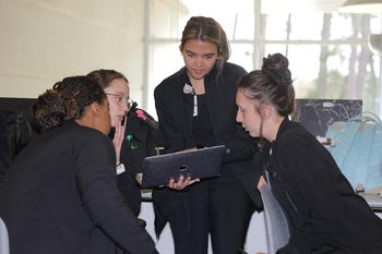 Four nursing students huddled around a laptop