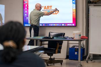 An instructor demonstrating digital art, on a wall mounted touch screen.